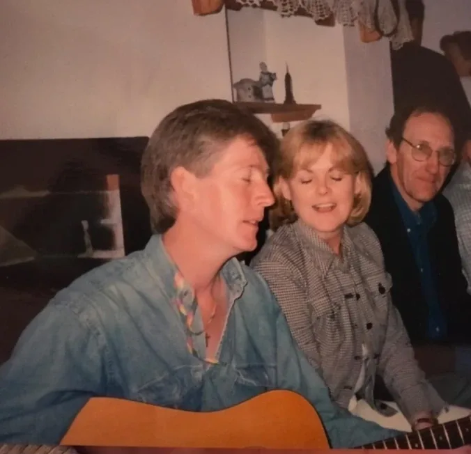 Older photo of two men and a child with a guitar